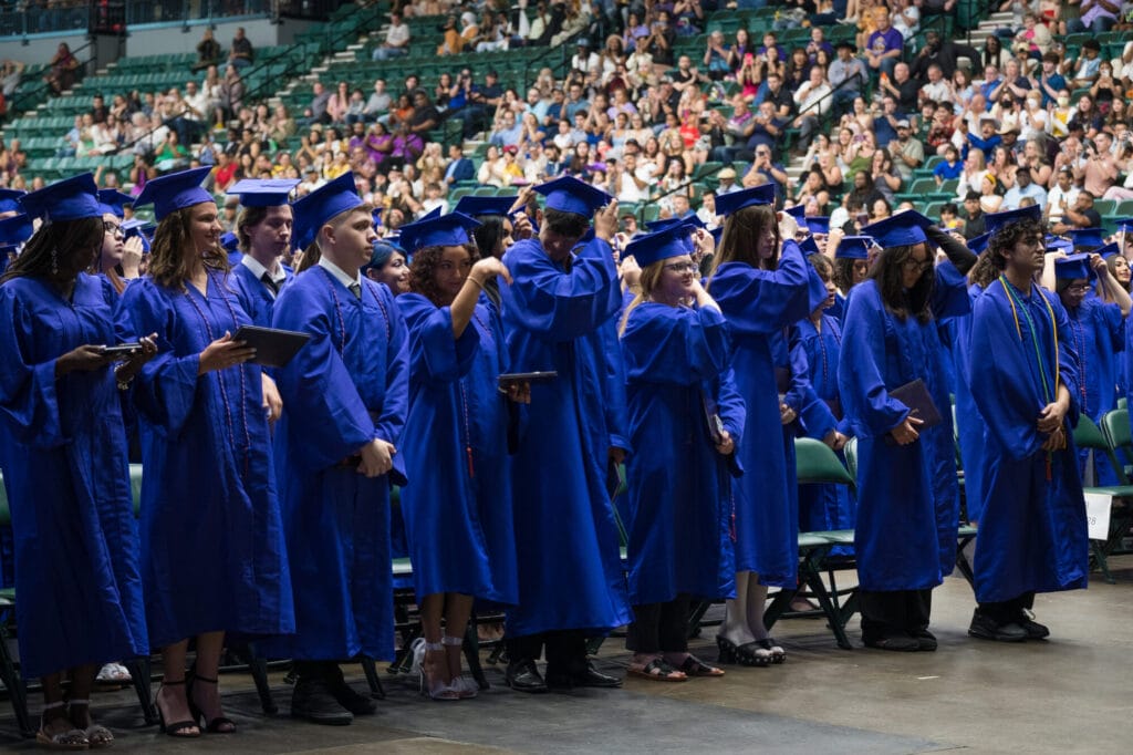 TVAH graduates holding diplomas and turning tassels.