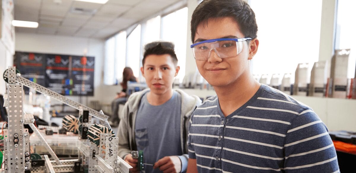 Two young men collaborate in a lab, examining a robot as part of their scientific research and innovation efforts.