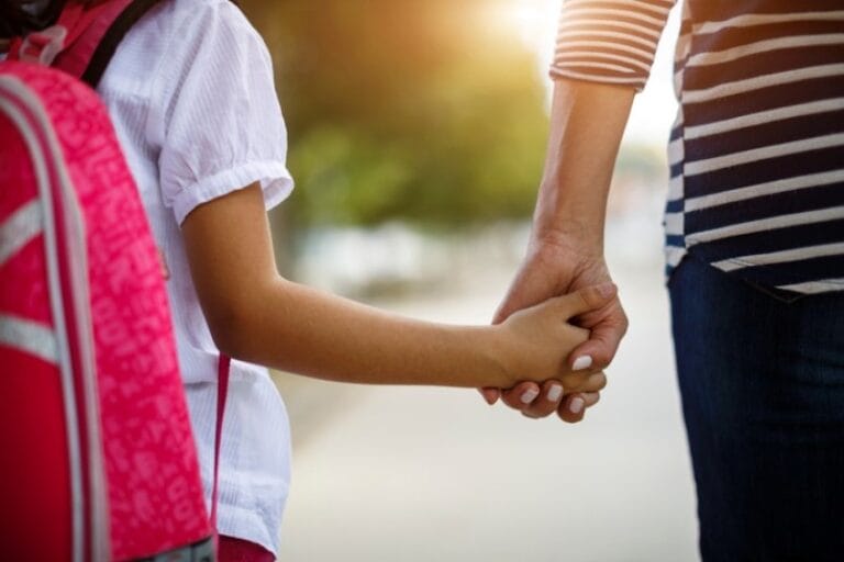 A woman gently holds hands with a child, symbolizing love and connection between them.